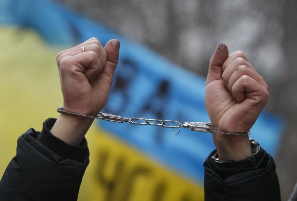 Pro-European integration supporter holds up handcuffs during a rally against newly approved laws near the presidential administration in Kiev