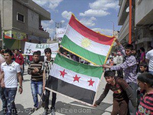 Manifestanti espongono la bandiera del Kurdistan e quella della Repubblica Araba di Siria.