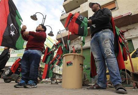 People hold Libyan national flags as preparations take place in the city for the upcoming celebrations to commemorate the second anniversary of the revolt against Muammar Gaddafi, in Benghazi